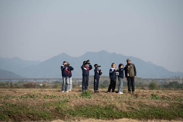 (251120) -- CHIZHOU, Nov. 20, 2025 (Xinhua) -- Students of Maotan Primary School observe birds under the guidance of a wild bird conservation volunteer at the Shibasuo provincial nature reserve in Chizhou City, east China's Anhui Province, Nov. 18, 2025.
  Maotan Primary School is adjacent to the Shibasuo provincial nature reserve. The reserve boasts abundant wildlife resources and protects mainly wintering waterfowl such as storks and geese, as well as the wetland ecosystem. It serves as a unique "nature classroom" for the school, especially in wetland conservation education.
  For years, the school has integrated wetland protection education into its daily teaching. Volunteers are invited to the school for wetland science popularization, and students are frequently organized for study tours in the wetlands. This teaching approach has deepened the children's understanding of wetland conservation. (Xinhua/Zhang Duan)