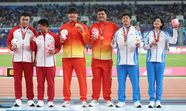 (251120) -- GUANGZHOU, Nov. 20, 2025 (Xinhua) -- Gold medalist Abuduaini Tuergong of Xinjiang, silver medalist Xing Jiadong of Shandong and bronze medalist Zhu Jiacheng of Zhejiang pose with their coaches during the awarding ceremony for the men's discus throw of athletics at China's 15th National Games in Guangzhou, south China's Guangdong Province, Nov. 20, 2025. (Xinhua/Huang Wei)