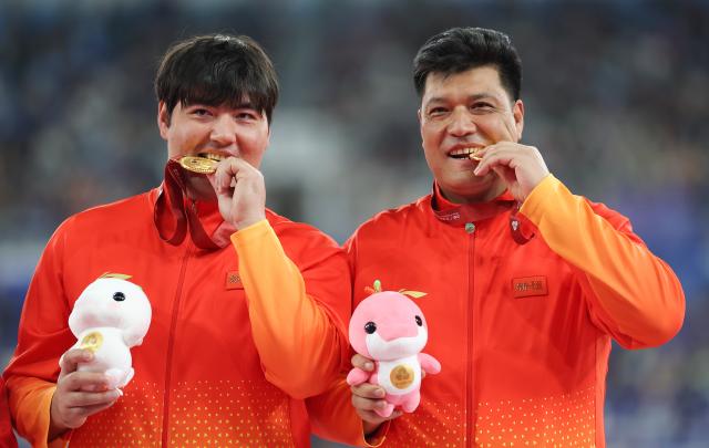 (251120) -- GUANGZHOU, Nov. 20, 2025 (Xinhua) -- Gold medalist Abuduaini Tuergong of Xinjiang poses with his coach during the awarding ceremony for the men's discus throw of athletics at China's 15th National Games in Guangzhou, south China's Guangdong Province, Nov. 20, 2025. (Xinhua/Huang Wei)