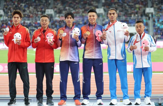 (251120) -- GUANGZHOU, Nov. 20, 2025 (Xinhua) -- Gold medalist Liu Dezhu of Guangxi, silver medalist Tao Peilin of Jiangsu and bronze medalist Xi Xiaoheng of Zhejiang pose with their coaches during the awarding ceremony for the men's 1500m of athletics at China's 15th National Games in Guangzhou, south China's Guangdong Province, Nov. 20, 2025. (Xinhua/Huang Wei)