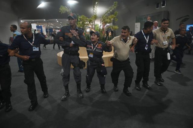 (251120) -- BELEM(BRAZIL), Nov. 20, 2025 (Xinhua) -- Security personnel form a human chain to guide people evacuating the venue of the 30th United Nations Climate Change Conference (COP30) after a fire broke out in Belem, Para state, Brazil, Nov. 20, 2025. A fire broke out on Thursday in a pavilion at the ongoing 30th UN Climate Change Conference in the Brazilian city of Belem, prompting evacuations by the fire department, according to local authorities. (Photo by Lucio Tavora/Xinhua)