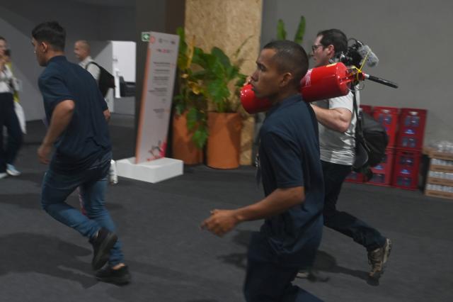 (251120) -- BELEM(BRAZIL), Nov. 20, 2025 (Xinhua) -- A staff member carrying a fire extinguisher runs inside the venue of the 30th United Nations Climate Change Conference (COP30) after a fire broke out in Belem, Para state, Brazil, Nov. 20, 2025. A fire broke out on Thursday in a pavilion at the ongoing 30th UN Climate Change Conference in the Brazilian city of Belem, prompting evacuations by the fire department, according to local authorities. (Photo by Lucio Tavora/Xinhua)