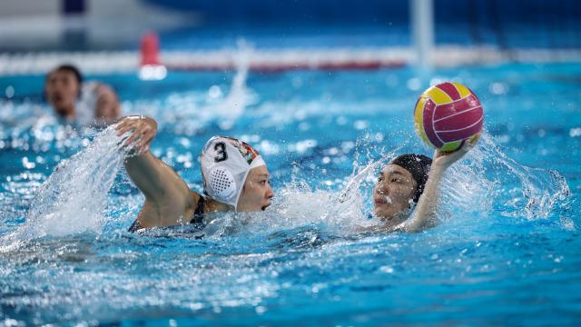 (251121) -- GUANGZHOU, Nov. 21, 2025 (Xinhua) -- Meng Xinyan (R) of Guangxi passes the ball during the women's water polo bronze medal match between Guangxi and Hunan at China's 15th National Games in Guangzhou, south China's Guangdong Province, Nov. 21, 2025. (Xinhua/Pan Yulong)