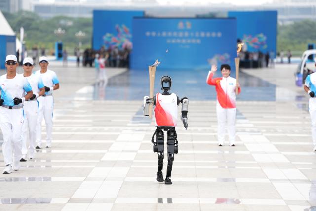 (251121) -- GUANGZHOU, Nov. 21, 2025 (Xinhua) -- Torch bearer humanoid robot "Kuavo" (front) runs during the torch relay for China's 15th National Games in Shenzhen, south China's Guangdong Province, Nov. 2, 2025. (Xinhua/Jiang Han)