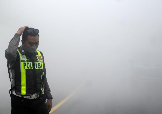 (251121) -- LUMAJANG, Nov. 21, 2025 (Xinhua) -- A police officer walks among smokes and volcanic materials erupted from the Semeru volcano at Sumberwuluh village in Lumajang regency, East Java, Indonesia, Nov. 21, 2025. Indonesia's Semeru volcano erupted on Wednesday, prompting the country's volcanology agency to raise the alert level to the maximum. (Photo by Sahlan Kurniawan/Xinhua)