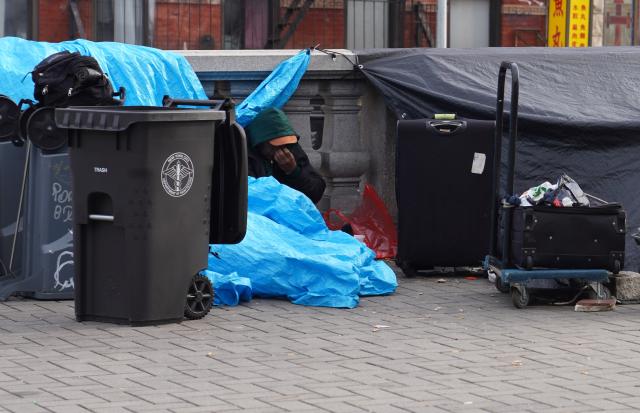 (251122) -- NEW YORK, Nov. 22, 2025 (Xinhua) -- A man with his luggage sits by a street near a shelter for the homeless in New York, the United States, on Nov. 21, 2025. It is estimated that more than 350,000 people were without home in New York City (NYC) by August this year, the highest level since the Great Depression of the 1930s, according to the Coalition for the Homeless. Most of them slept in NYC shelters or temporarily doubled-up in the homes of others, and thousands slept unsheltered on streets, parks and subways. (Xinhua/Zhang Fengguo)