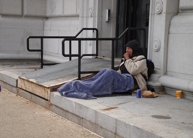 (251122) -- NEW YORK, Nov. 22, 2025 (Xinhua) -- A man sits by a street near a shelter for the homeless in New York, the United States, on Nov. 21, 2025. It is estimated that more than 350,000 people were without home in New York City (NYC) by August this year, the highest level since the Great Depression of the 1930s, according to the Coalition for the Homeless. Most of them slept in NYC shelters or temporarily doubled-up in the homes of others, and thousands slept unsheltered on streets, parks and subways. (Xinhua/Zhang Fengguo)