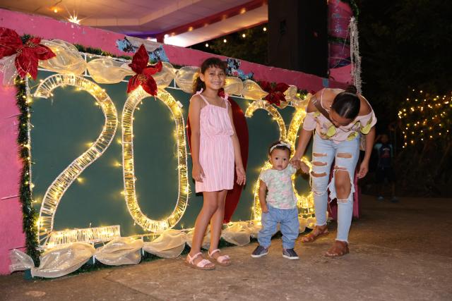 (251122) -- PUERTO CABEZAS, Nov. 22, 2025 (Xinhua) -- This photo taken on Nov. 19, 2025 shows people standing in front of new year decorations in Puerto Cabezas, in North Caribbean Coast Autonomous Region, Nicaragua. Puerto Cabezas, located on Nicaragua's eastern Caribbean coast, serves as the capital of the North Caribbean Coast Autonomous Region (RACCN). This distinctive port city features a hot, humid climate, scenic landscapes, and abundant natural resources. (Xinhua/Li Mengxin)