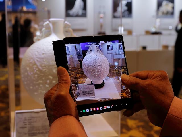 (251122) -- LOS ANGELES, Nov. 22, 2025 (Xinhua) -- A visitor takes photos of an artwork at an exhibition showcasing China's Dehua white porcelain in Los Angeles, the United States, Nov. 21, 2025. The exhibition opened here Friday, drawing over 100 attendees from both countries and aiming to highlight traditional Chinese culture while promoting cross-cultural exchange.
  Titled "The Aesthetics of Harmony: Blanc de Chine, Porcelain from Dehua," the exhibition featured around 100 finely crafted ceramic artworks and photographic pieces. (Photo by Qiu Chen/Xinhua)