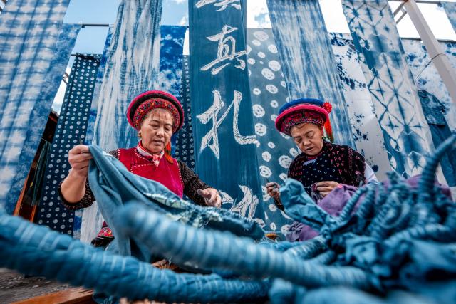 (251123) -- BEIJING, Nov. 23, 2025 (Xinhua) -- Duan Yinmei (L), an inheritor of the tie-dye technique of Bai ethnic group, and handicraftsman Duan Lilan untie knots on fabrics in a dyehouse in Zhoucheng Village of Dali Bai Autonomous Prefecture, southwest China's Yunnan Province, Nov. 21, 2025.
  Known as the hometown of the tie-dye technique of Bai ethnic group, Zhoucheng Village hosts over 200 households engaging in tie-dye businesses, with the number of employees exceeding 4,000. (Xinhua/Hu Chao)