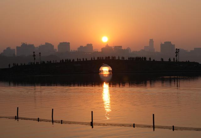 (251123) -- HANGZHOU, Nov. 23, 2025 (Xinhua) -- Tourists enjoy the scenery at sunrise at the West Lake scenic area in Hangzhou, east China's Zhejiang Province, Nov. 23, 2025.
  The weather in Hangzhou has been fine in recent days. Many tourists get up early in the morning to visit West Lake and enjoy the beautiful winter scenery here. (Xinhua/Han Chuanhao)