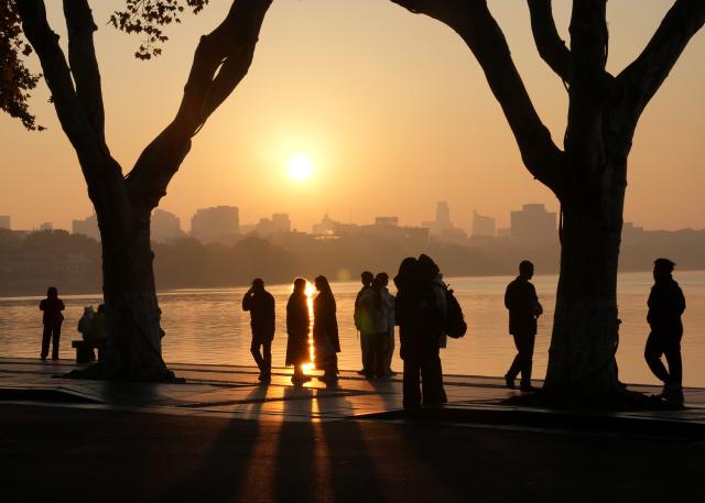 (251123) -- HANGZHOU, Nov. 23, 2025 (Xinhua) -- Tourists enjoy the scenery at sunrise at the West Lake scenic area in Hangzhou, east China's Zhejiang Province, Nov. 23, 2025.
  The weather in Hangzhou has been fine in recent days. Many tourists get up early in the morning to visit West Lake and enjoy the beautiful winter scenery here. (Xinhua/Han Chuanhao)