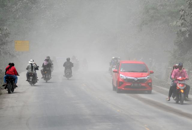 (251123) -- JAKARTA, Nov. 23, 2025 (Xinhua) -- People ride vehicles amid smoke and ash erupted from the Semeru volcano at Sumberwuluh village in Lumajang regency, East Java, Indonesia, Nov. 23, 2025. Indonesia's Semeru volcano erupted on Wednesday, prompting the country's volcanology agency to raise the alert level to the maximum. (Photo by Sahlan Kurniawan/Xinhua)