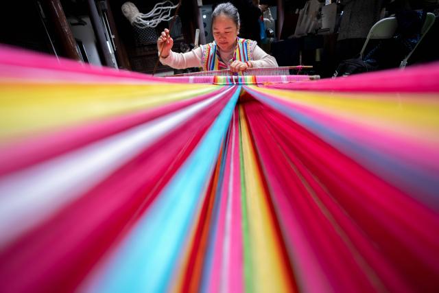 (251123) -- DALI, Nov. 23, 2025 (Xinhua) -- A staff member demonstrates the skills of making Dulong blanket during a promotion week for intangible cultural heritage brands in Dali, southwest China's Yunnan Province, Nov. 23, 2025. More than 120 brands of intangible cultural heritage took part in the brand promotion week which opened here on Sunday. (Xinhua/Hu Chao)