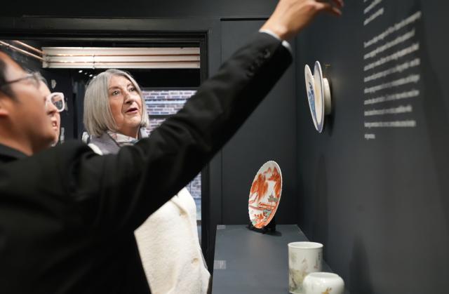 (251124) -- STOKE-ON-TRENT, Nov. 24, 2025 (Xinhua) -- Visitors listen to a Chinese curator explaining Jingdezhen porcelain pieces on display at the Spode Museum in Stoke-on-Trent, Britain, Nov. 22, 2025.
  TO GO WITH "Feature: Shared blue-and-white legacies link Britain, China ceramic hubs" (Xinhua/Zheng Bofei)