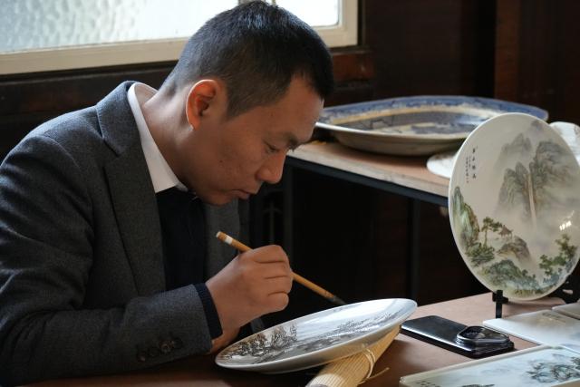 (251124) -- STOKE-ON-TRENT, Nov. 24, 2025 (Xinhua) -- A faculty member from Jingdezhen Ceramic University demonstrates overglaze painting on the sidelines of an international ceramics symposium in Stoke-on-Trent, Britain, Nov. 22, 2025.
  TO GO WITH "Feature: Shared blue-and-white legacies link Britain, China ceramic hubs" (Xinhua/Zheng Bofei)