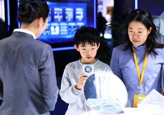 (251124) -- BEIJING, Nov. 24, 2025 (Xinhua) -- A child visits the 22nd China International Semiconductor Expo in Beijing, capital of China, Nov. 23, 2025. The expo opened here on Sunday. (Xinhua/Pan Xu)