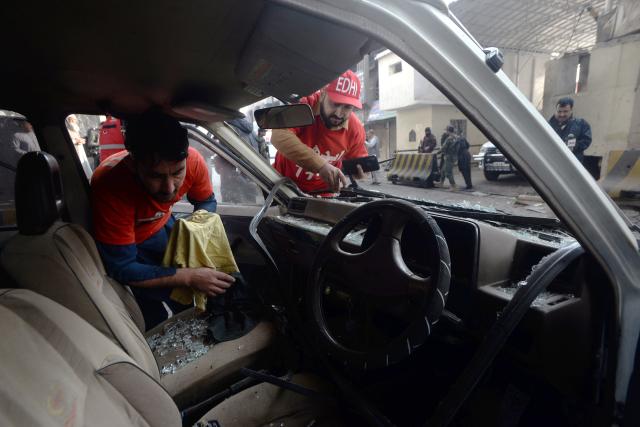 (251124) -- PESHAWAR, Nov. 24, 2025 (Xinhua) -- Rescuers inspect a damaged vehicle at the blast site in Peshawar, northwest Pakistan, on Nov. 24, 2025. At least three security personnel were killed and five others injured on Monday morning in an attack at the Federal Constabulary's headquarters in Pakistan's northwest Khyber Pakhtunkhwa provincial capital of Peshawar, police said. (Photo by Umar Qayyum/Xinhua)