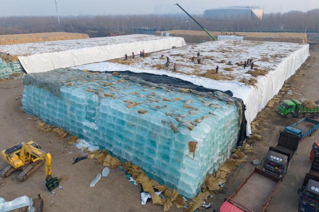 (251124) -- HARBIN, Nov. 24, 2025 (Xinhua) -- An aerial drone photo taken on Nov. 24, 2025 shows staff members removing the covering on the ice cubes at an ice storage site for the Harbin Ice-Snow World in Harbin, northeast China's Heilongjiang Province. The 27th edition of the Harbin Ice-Snow World, a renowned seasonal theme park in Harbin, will officially begin construction on Nov. 25 this year. (Xinhua/Xie Jianfei)