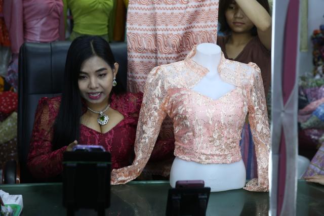 (251124) -- YANGON, Nov. 24, 2025 (Xinhua) -- A livestream seller promotes a set of clothes during a TikTok livestream in Yangon, Myanmar, Nov. 24, 2025. TO GO WITH "Feature: Myanmar's livestream sellers thrive in TikTok's booming marketplace" (Xinhua/Myo Kyaw Soe)