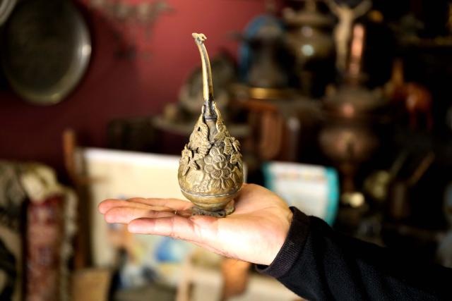 (251124) -- BAGHDAD, Nov. 24, 2025 (Xinhua) -- The owner of an antique shop displays his collection in a local culture market in Baghdad, Iraq, Nov. 24, 2025. (Xinhua/Khalil Dawood)