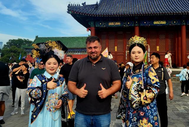 (251125) -- BELGRADE, Nov. 25, 2025 (Xinhua) -- This undated photo shows Serbian documentary producer Bosko Kozarski (C) posing for a photo with tourists in traditional Chinese costumes at Tiantan (Temple of Heaven) Park in Beijing, capital of China. TO GO WITH "Feature: Serbian documentary producer finds inspiration in Beijing's blend of history, modern life" (Xinhua)