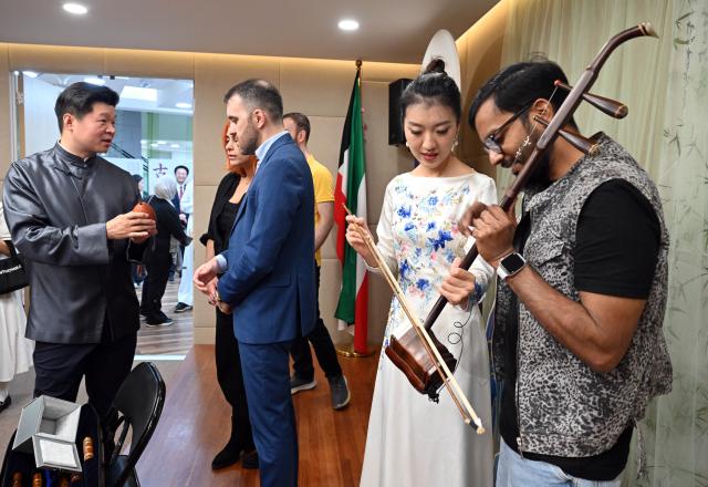 (251125) -- HAWALLI GOVERNORATE, Nov. 25, 2025 (Xinhua) -- Visitors interact with Chinese musicians at the China Cultural Center in Hawalli Province, Kuwait, on Nov. 24, 2025. The China Cultural Center in Kuwait hosted a Chamber Concert of Chinese Classical Music event under the theme "Traditional Rhythm & New Vibe" as part of its Chinese Culture Series -- Night of Chinese Language. (Photo by Asad/Xinhua)