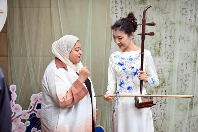 (251125) -- HAWALLI GOVERNORATE, Nov. 25, 2025 (Xinhua) -- A visitor interacts with a Chinese musician at the China Cultural Center in Hawalli Province, Kuwait, on Nov. 24, 2025. The China Cultural Center in Kuwait hosted a Chamber Concert of Chinese Classical Music event under the theme "Traditional Rhythm & New Vibe" as part of its Chinese Culture Series -- Night of Chinese Language. (Photo by Asad/Xinhua)