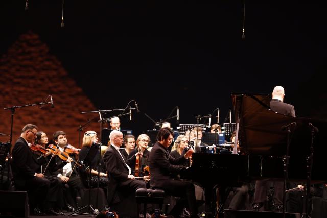 (251125) -- GIZA, Nov. 25, 2025 (Xinhua) -- Chinese pianist Lang Lang performs alongside the British Royal Philharmonic Concert Orchestra during the Pyramids Echo (TPE) festival at the Giza Pyramids scenic spot in Giza, Egypt, Nov. 24, 2025. TO GO WITH "Roundup: Chinese piano virtuoso Lang Lang captivates audience at Egypt's pyramids concert" (Xinhua/Ahmed Gomaa)