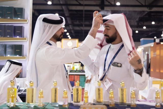 (251125) -- MANAMA, Nov. 25, 2025 (Xinhua) -- A man sprays perfume on another visitor at the "Scent Arabia" exhibition in Manama, Bahrain, Nov. 25, 2025. The "Scent Arabia" exhibition opened at Exhibition World Bahrain in Manama, Bahrain on Tuesday, featuring over 100 brands from the Gulf countries and worldwide, including perfumes, home fragrances and Arabian incense. The event is scheduled to run through Nov. 29. (Xinhua/Chen Junqing)