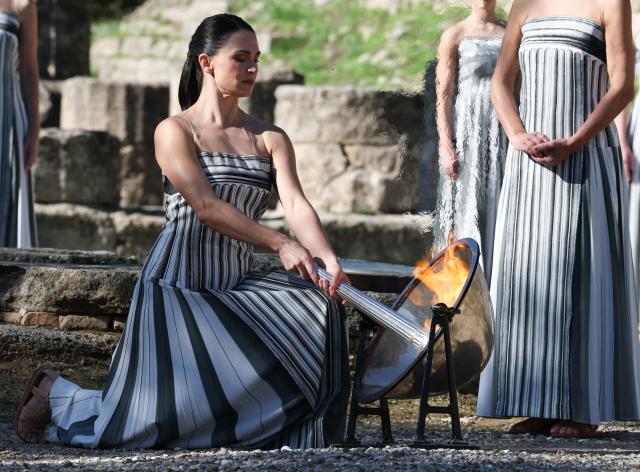 (251126) -- ANCIENT OLYMPIA, Nov. 26, 2025 (Xinhua) -- Actress Mary Mina, in the role of an ancient Greek High Priestess, lights the flame during the dress rehearsal of the Olympic flame lighting ceremony for the Milan-Cortina 2026 Winter Olympic Games in Ancient Olympia, Greece, on Nov. 24, 2025. (Xinhua/Li Jing)