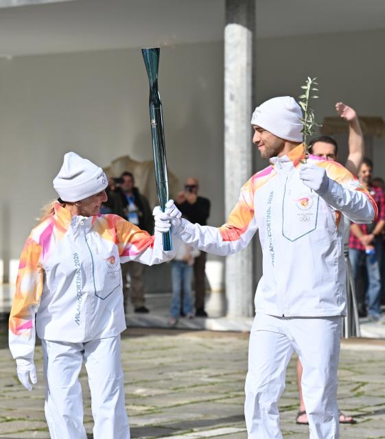 (251126) -- ANCIENT OLYMPIA, Nov. 26, 2025 (Xinhua) -- The first torchbearer, Greek rower Petros Gkaidatzis (R) and second torchbearer, Italian former cross-country skier Stefania Belmondo carry the torch during the torch relay after the Olympic flame lighting ceremony for the Milan-Cortina 2026 Winter Olympic Games in Ancient Olympia, Greece, on Nov. 26, 2025. (Xinhua/Lyu You)