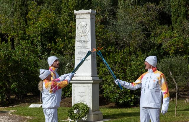(251126) -- ANCIENT OLYMPIA, Nov. 26, 2025 (Xinhua) -- Torchbearers Greek rower Petros Gkaidatzis (C), Italian former cross-country skier Stefania Belmondo (L) and Italian former luger Armin Zoeggeler are seen in front of the Coubertin monument during the torch relay after the Olympic flame lighting ceremony for the Milan-Cortina 2026 Winter Olympic Games in Ancient Olympia, Greece, on Nov. 26, 2025. (Photo by Marios Lolos/Xinhua)