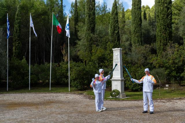 (251126) -- ANCIENT OLYMPIA, Nov. 26, 2025 (Xinhua) -- Torchbearers Greek rower Petros Gkaidatzis (C), Italian former cross-country skier Stefania Belmondo (L) and Italian former luger Armin Zoeggeler are seen in front of the Coubertin monument during the torch relay after the Olympic flame lighting ceremony for the Milan-Cortina 2026 Winter Olympic Games in Ancient Olympia, Greece, on Nov. 26, 2025. (Photo by Marios Lolos/Xinhua)