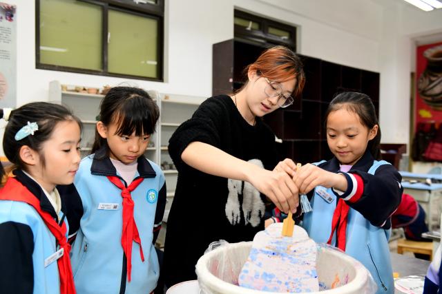 (251126) -- JINAN, Nov. 26, 2025 (Xinhua) -- A teacher guides students to make lacquer fans at a primary school in Shizhong District of Jinan City, east China's Shandong Province, Nov. 25, 2025. In recent years, authorities in Shizhong District of Jinan City have been encouraging local schools to enhance aesthetic education by exposing their students to diverse arts-related extracurricular programs. (Xinhua/Guo Xulei)