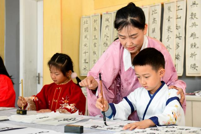 (251126) -- JINAN, Nov. 26, 2025 (Xinhua) -- A teacher guides students in practicing calligraphy at a primary school in Shizhong District of Jinan City, east China's Shandong Province, Nov. 26, 2025. In recent years, authorities in Shizhong District of Jinan City have been encouraging local schools to enhance aesthetic education by exposing their students to diverse arts-related extracurricular programs. (Xinhua/Guo Xulei)
