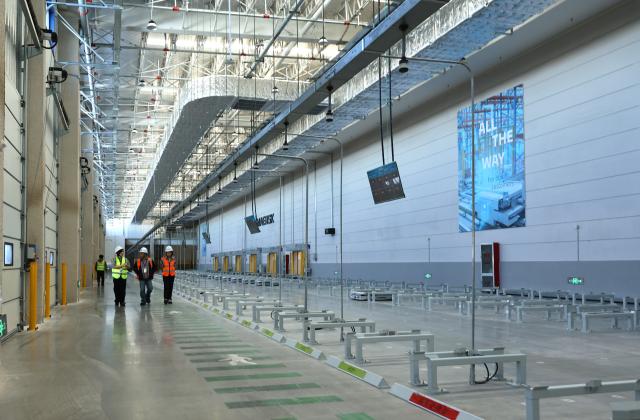 (251126) -- SHANGHAI, Nov. 26, 2025 (Xinhua) -- Staff members are pictured next to the working area of self-navigating trolleys inside a warehouse of the Maersk Lin-gang Flagship Logistics Center in east China's Shanghai, on Nov. 26, 2025. The Maersk Lin-gang Flagship Logistics Center, located at the Yangshan special comprehensive bonded zone in the Lingang new area of the China (Shanghai) Pilot Free Trade Zone (FTZ), has been officially opened to business.
   This comprehensive logistics warehouse, with a storage area of about 147,000 square meters, costed a total investment of about 1 billion yuan (about 141.24 million US dollars). (Xinhua/Fang Zhe)