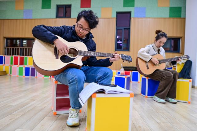 (251126) -- NINGBO, Nov. 26, 2025 (Xinhua) -- Citizens play guitar during a night-time class held at the youth activity center in Jiangbei District of Ningbo, east China's Zhejiang Province, Nov. 26, 2025. Starting from 2024, Jiangbei District in Ningbo has integrated educational and training resources from universities, hospitals, law firms and other enterprises and institutions in a night-time school project, offering courses in foreign languages, dance, music and fashion design, among others. It has enrolled more than 9,600 citizens by now. (Xinhua/Jiang Han)