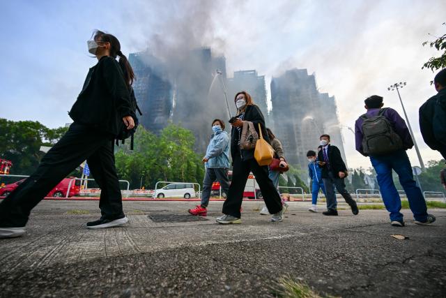 (251127) -- HONG KONG, Nov. 27, 2025 (Xinhua) -- People walk past a residential area fire site in Hong Kong, south China, Nov. 27, 2025. Three men have been arrested for suspected manslaughter in a fire that broke out in Wang Fuk Court, a residential area in Tai Po of Hong Kong, on Wednesday afternoon, the Hong Kong Police Force said at a press briefing on Thursday.
   The fire had left 44 people dead and 45 others injured by early Thursday morning, the police said. (Xinhua/Zhu Wei)