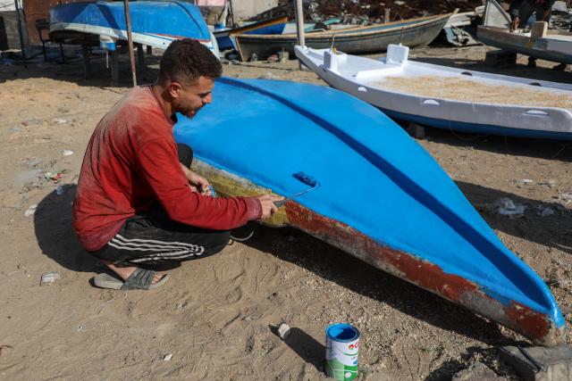 (251127) -- GAZA CITY, Nov. 27, 2025 (Xinhua) -- A Palestinian repairs a fishing boat destroyed during the Israeli war on the Gaza Strip, inside the seaport in west of Gaza City, on Nov. 27, 2025. (Photo by Rizek Abdeljawad/Xinhua)