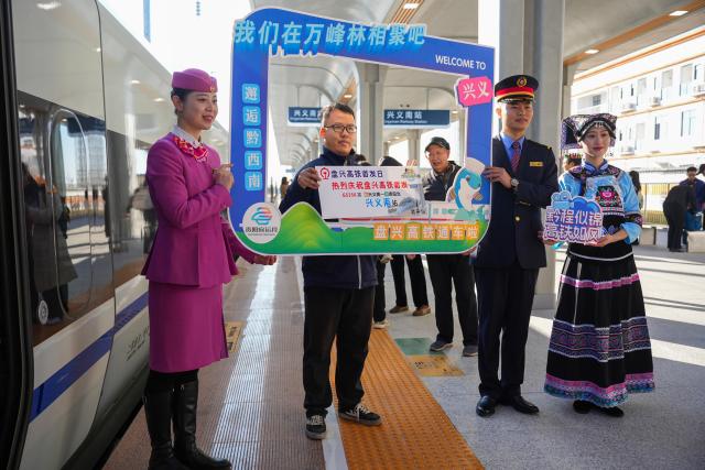 (251128) -- GUIYANG, Nov. 28, 2025 (Xinhua) -- A passenger poses for a group photo with staff members at Xingyi South Railway Station in Xingyi, southwest China's Guizhou Province, Nov. 28, 2025. With a design speed of 250 kilometers per hour, the 99-kilometer-long Panzhou-Xingyi high-speed railway officially opened to traffic on Friday, which will further enhance regional transportation networks and promote local economic development. (Photo by Long Jianrui/Xinhua)