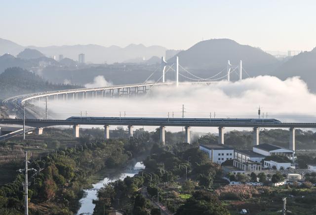 (251128) -- GUIYANG, Nov. 28, 2025 (Xinhua) -- A bullet train runs on a grand bridge of the Panzhou-Xingyi high-speed railway in Xingyi, southwest China's Guizhou Province, Nov. 28, 2025. With a design speed of 250 kilometers per hour, the 99-kilometer-long Panzhou-Xingyi high-speed railway officially opened to traffic on Friday, which will further enhance regional transportation networks and promote local economic development. (Xinhua/Yang Wenbin)