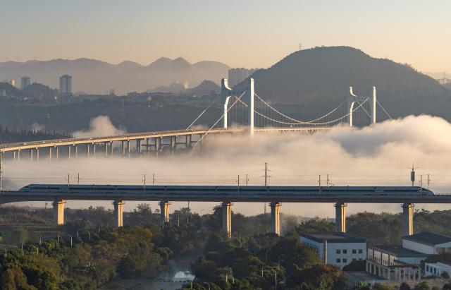 (251128) -- GUIYANG, Nov. 28, 2025 (Xinhua) -- A drone photo taken on Nov. 28, 2025 shows a bullet train running on a grand bridge of the Panzhou-Xingyi high-speed railway in Xingyi, southwest China's Guizhou Province. With a design speed of 250 kilometers per hour, the 99-kilometer-long Panzhou-Xingyi high-speed railway officially opened to traffic on Friday, which will further enhance regional transportation networks and promote local economic development. (Photo by Long Jianrui/Xinhua)