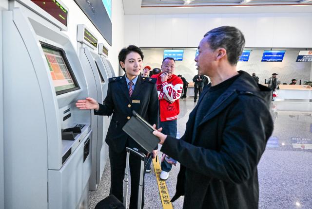 (251128) -- GUIYANG, Nov. 28, 2025 (Xinhua) -- A staff member helps a passenger buy tickets at Xingyi South Railway Station in Xingyi, southwest China's Guizhou Province, Nov. 28, 2025. With a design speed of 250 kilometers per hour, the 99-kilometer-long Panzhou-Xingyi high-speed railway officially opened to traffic on Friday, which will further enhance regional transportation networks and promote local economic development. (Xinhua/Yang Wenbin)