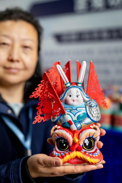 (251128) -- KUNMING, Nov. 28, 2025 (Xinhua) -- A staff member displays a Lord Rabbit, known as Tu'er Ye in Chinese (a traditional handicraft and a festive clay toy for children, especially in Beijing), during the 2025 intangible cultural heritage (ICH) brand promotion week in Dali City, southwest China's Yunnan Province, Nov. 23, 2025. TO GO WITH "Across China: Young Chinese revive, transform ancient crafts for modern markets" (Xinhua/Hu Chao)