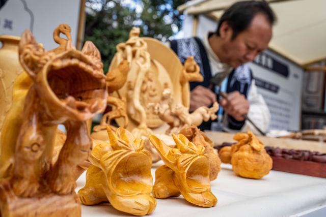 (251128) -- KUNMING, Nov. 28, 2025 (Xinhua) -- Yang Huanpei, a provincial-level inheritor for Jianchuan Wood Carving, demonstrates skills during the 2025 intangible cultural heritage (ICH) brand promotion week in Dali City, southwest China's Yunnan Province, Nov. 23, 2025. TO GO WITH "Across China: Young Chinese revive, transform ancient crafts for modern markets" (Xinhua/Hu Chao)