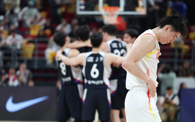 (251129) -- BEIJING, Nov. 29, 2025 (Xinhua) -- Cheng Shuaipeng (R) of China reacts as players of South Korea celebrate victory after the Group B match between China and South Korea at the FIBA Basketball World Cup Asian Qualifiers in Beijing, capital of China, Nov. 28, 2025. (Xinhua/Wang Kaiyan)