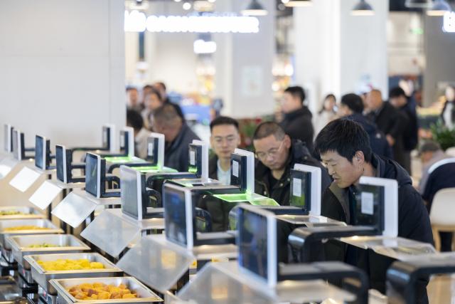 (251129) -- XIONG'AN, Nov. 29, 2025 (Xinhua) -- People choose food at an AI-powered canteen in Wenhua community in Xiong'an New Area, north China's Hebei Province, Nov. 25, 2025. The Xiong'an New Area, designed to relieve Beijing of its non-essential functions, has been leveraging smart and considerate public services to facilitate daily life of relocated residents.
   At Wenhua community in the startup section of Xiong'an New Area, an AI-powered canteen serves as a vivid example of how emerging consumption scenarios makes people feel better with their lives.
   At the canteen, automatic settlement system quickly verifies a customer's identity through facial recognition technology, and associates the food tray with his or her personal information to ensure a seamless payment process. Moreover, the serving zone inside the canteen also has smart devices capable of body weighing, calorie intake-tracking, detailed health status reporting as well as personalized dietary suggestions.
   The Chunmingbei community canteen in Rongdong District of the Xiong'an New Area, for its part, helps ease the burden on working parents by providing affordable dinners for their school-attending children. Nanwenying community canteen, also in Rongdong, offers tiered discounts to senior diners of 60 and above on their meals.
    Besides community canteens, community book stores and supermarkets further add to the convenience of local residents. Xiong'an New Area is building a well-managed and friendly community through meticulous public services. (Xinhua/Wu Zhizun)