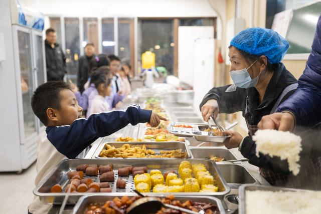(251129) -- XIONG'AN, Nov. 29, 2025 (Xinhua) -- Children choose food at a canteen in Chunmingbei community in Xiong'an New Area, north China's Hebei Province, Nov. 25, 2025. The Xiong'an New Area, designed to relieve Beijing of its non-essential functions, has been leveraging smart and considerate public services to facilitate daily life of relocated residents.
   At Wenhua community in the startup section of Xiong'an New Area, an AI-powered canteen serves as a vivid example of how emerging consumption scenarios makes people feel better with their lives.
   At the canteen, automatic settlement system quickly verifies a customer's identity through facial recognition technology, and associates the food tray with his or her personal information to ensure a seamless payment process. Moreover, the serving zone inside the canteen also has smart devices capable of body weighing, calorie intake-tracking, detailed health status reporting as well as personalized dietary suggestions.
   The Chunmingbei community canteen in Rongdong District of the Xiong'an New Area, for its part, helps ease the burden on working parents by providing affordable dinners for their school-attending children. Nanwenying community canteen, also in Rongdong, offers tiered discounts to senior diners of 60 and above on their meals.
    Besides community canteens, community book stores and supermarkets further add to the convenience of local residents. Xiong'an New Area is building a well-managed and friendly community through meticulous public services. (Xinhua/Wu Zhizun)