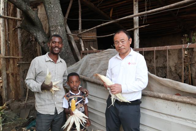 (251130) -- ADDIS ABABA, Nov. 30, 2025 (Xinhua) -- Abu Negash (L), with a newly-harvested ear of corn, poses for a photo with his son and a Chinese agricultural expert at Godino Jitu Village in Oromia Region, Ethiopia, on Nov. 26, 2025.
  TO GO WITH "Feature: Chinese experts drive integrated farming, transforming rural livelihoods in Ethiopia" (Xinhua/Liu Fangqiang)
